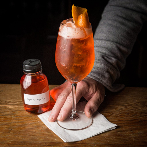 Aperol Spritz from our to-go cocktail program, served in a wine glass