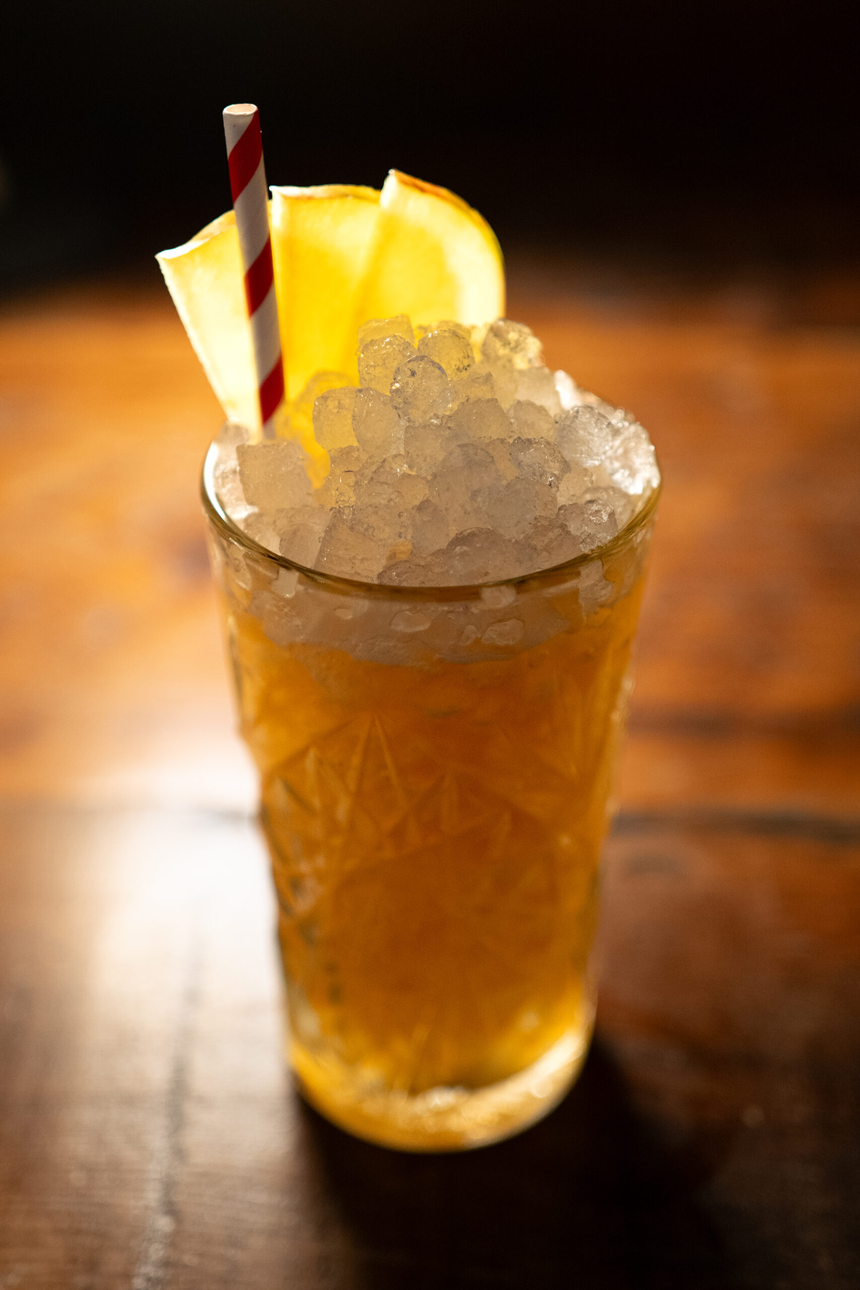 A scotch whisky and apple cider cocktail in a tall glass with crushed ice and a garnish of apple slices.